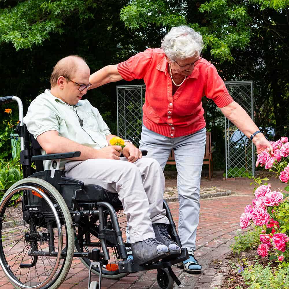 Mitarbeiterin besucht mit einem Bewohner den Garten